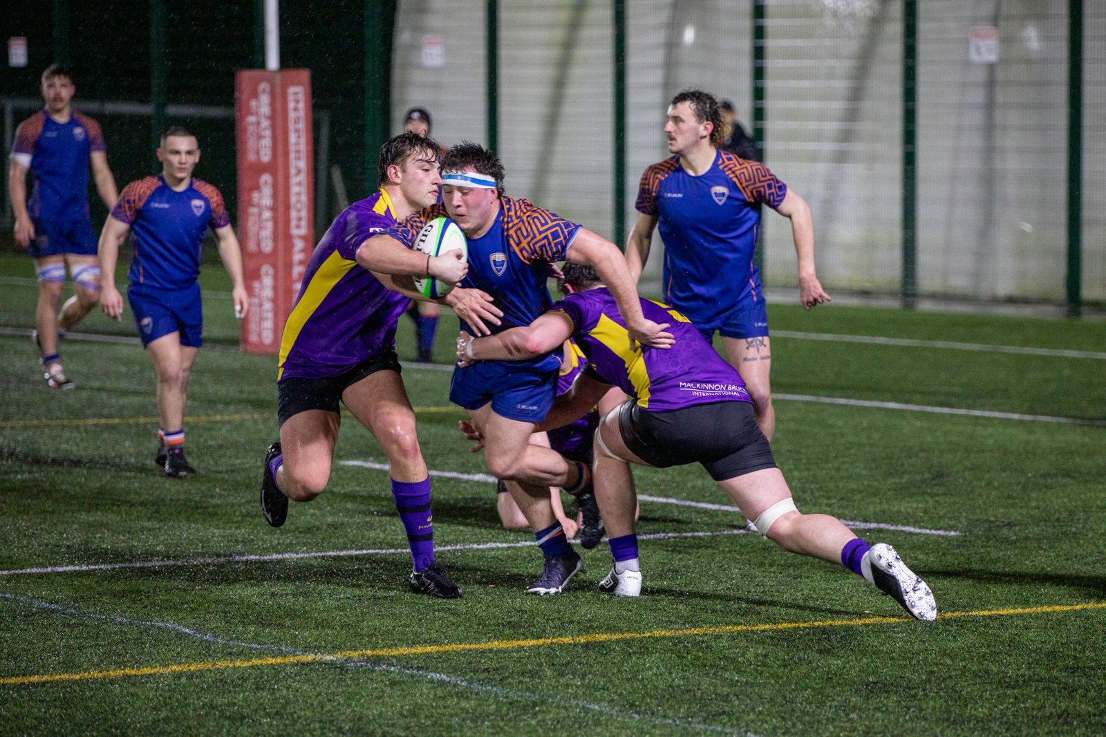 Rugby players in action during a night match in Manchester, showcasing teamwork and sportsmanship.