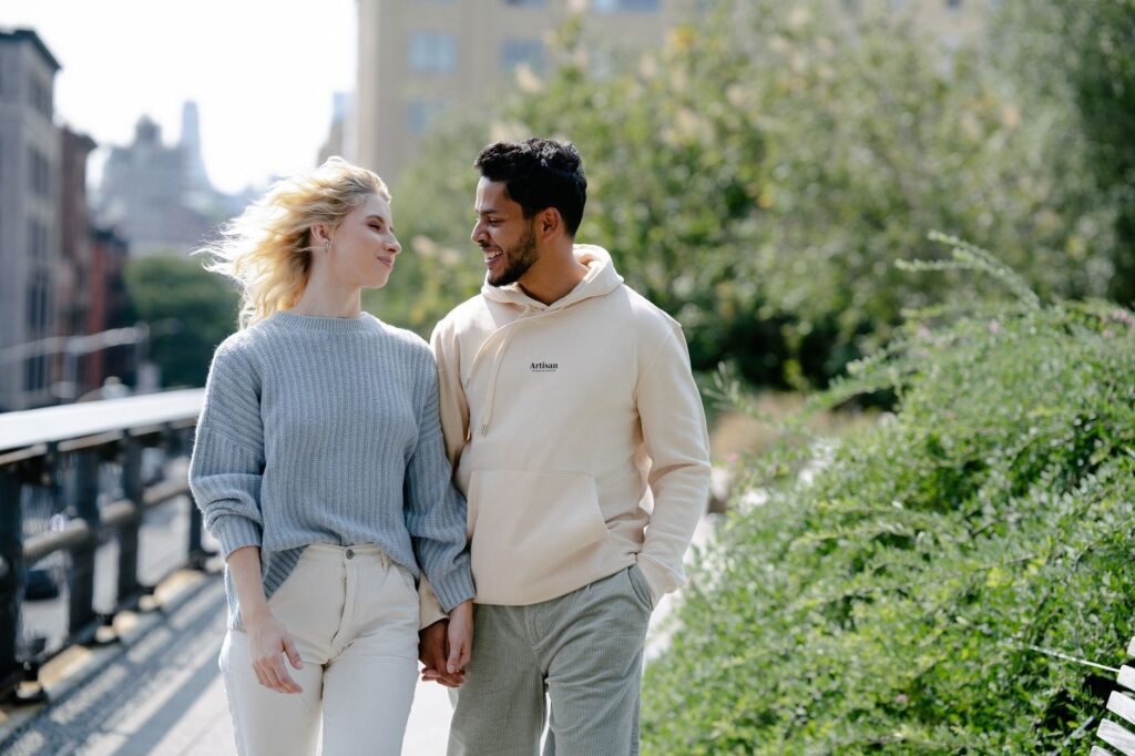 Cheerful couple holding hands and walking together through an urban park on a sunny day.