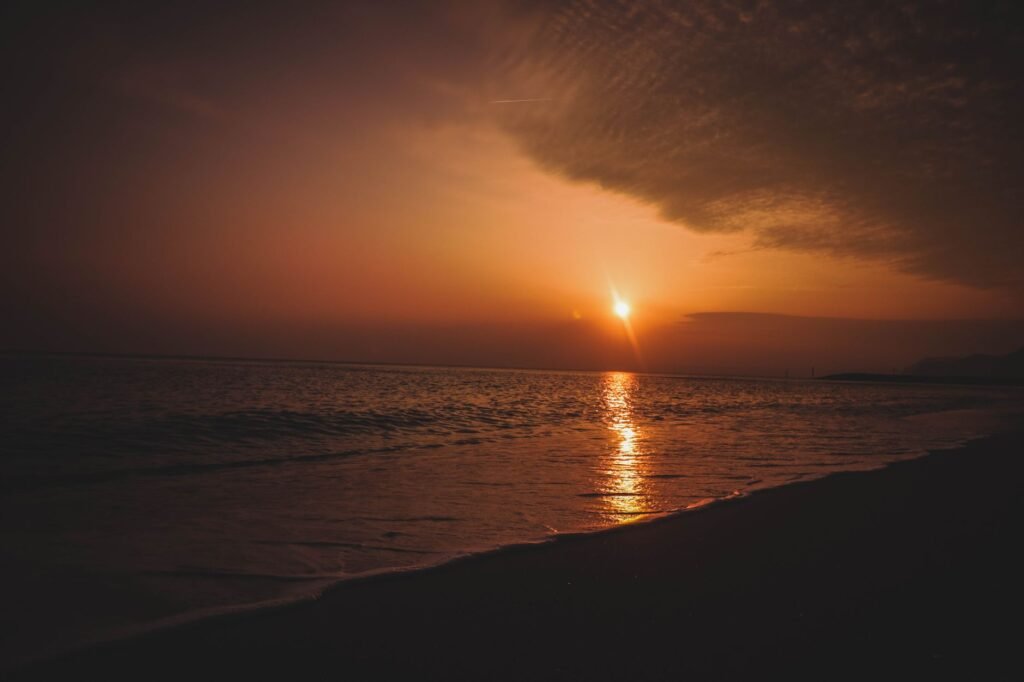 Capture a breathtaking sunset at West Bay, England, with vivid colors reflecting on calm waters.