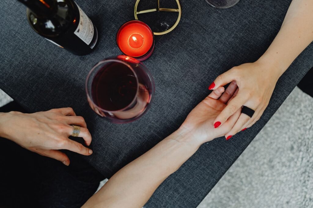 Couple holding hands over wine and candle at a romantic dinner setting.