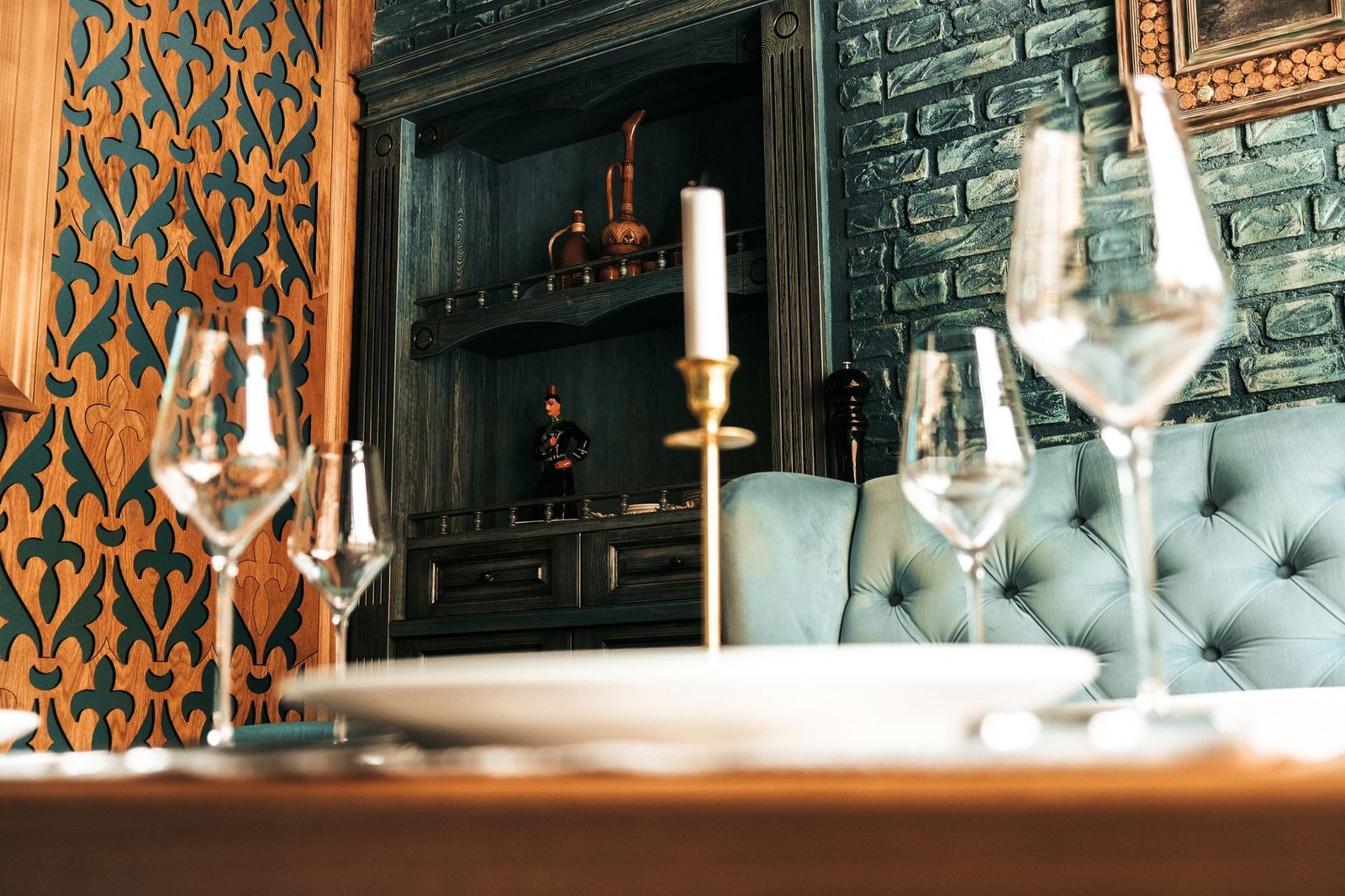 Close-up of a beautifully set table with glassware and a candle in an elegant restaurant interior.