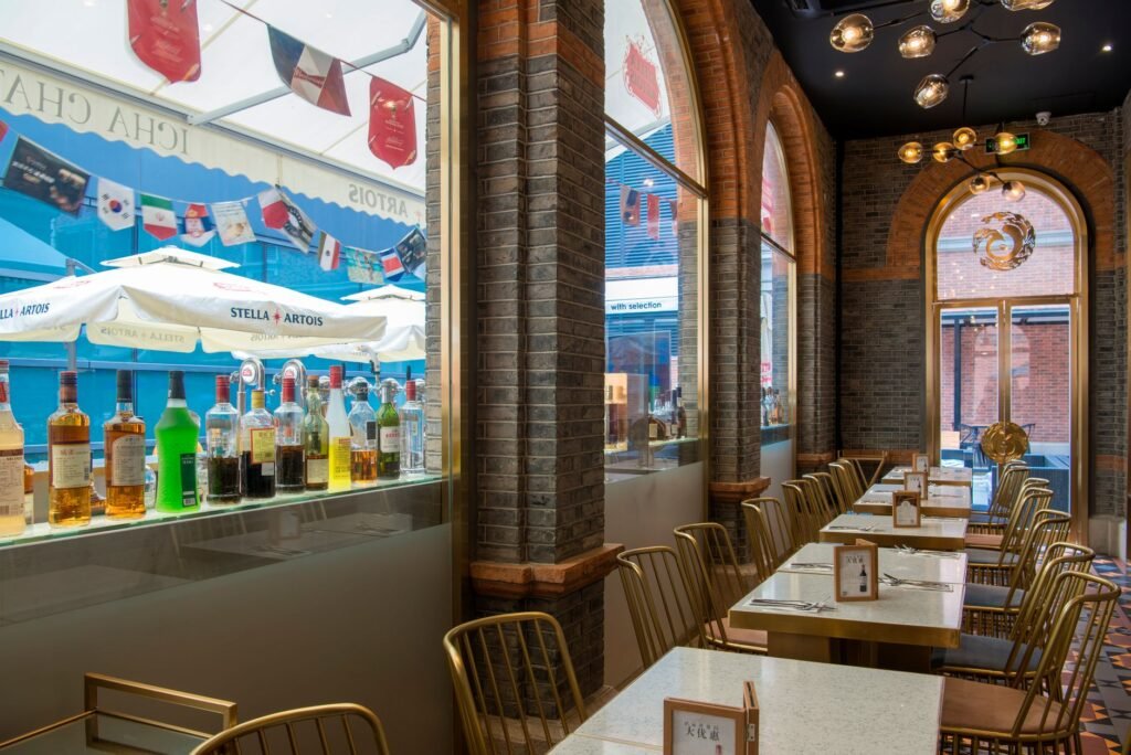 Chic restaurant interior showcasing a variety of alcohol bottles on display near large windows.