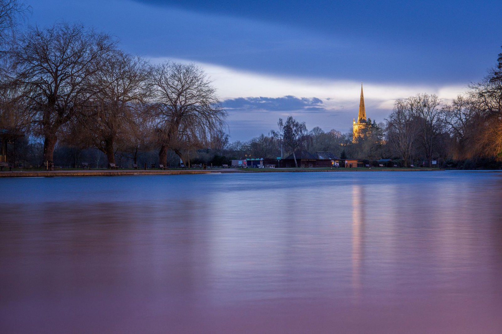 Tranquil twilight view of a river and church spire reflecting calm serenity.