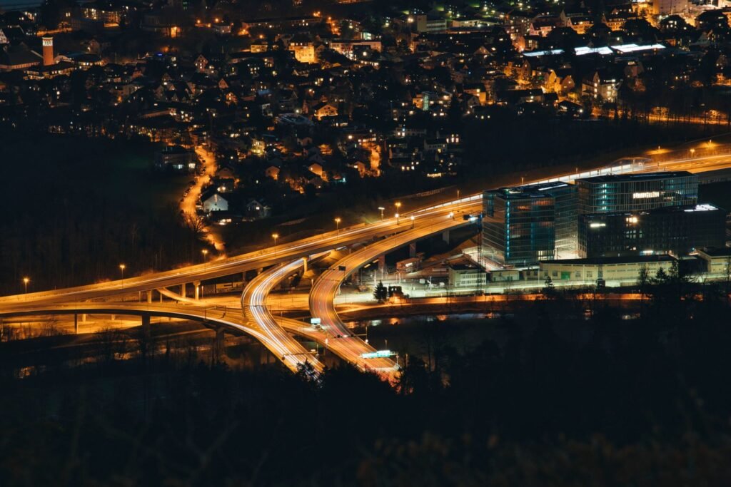 Highway curves through a lit cityscape at night, showcasing vibrant urban life.