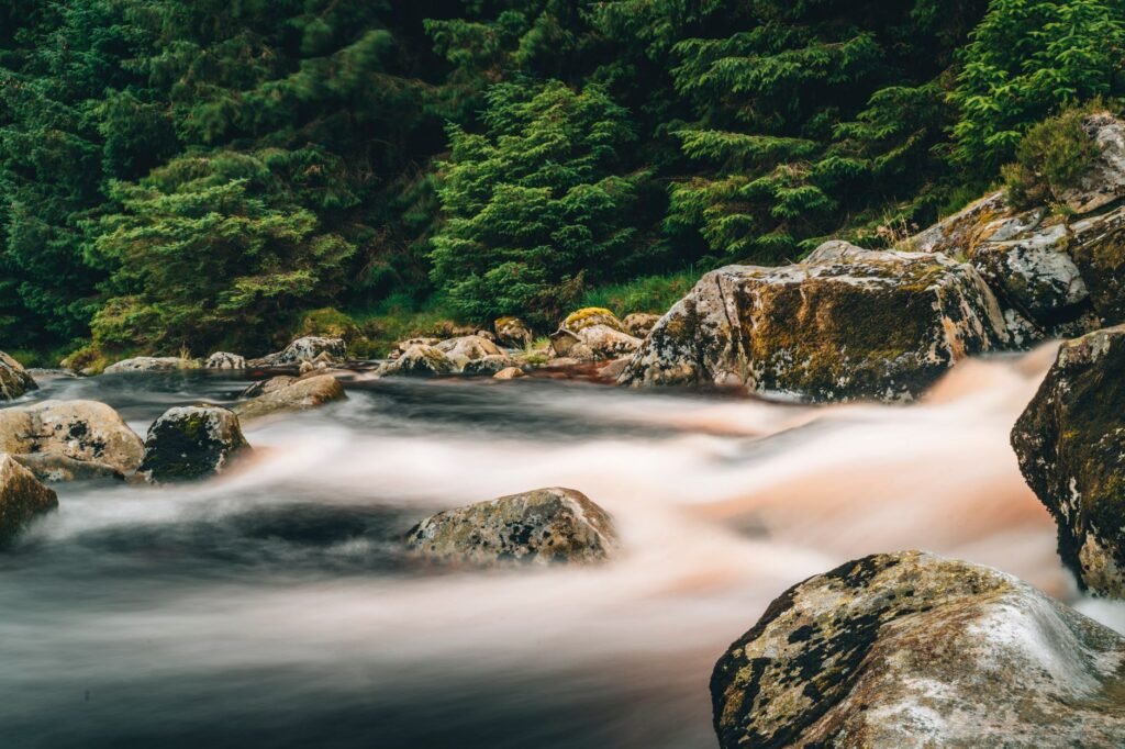 Peaceful river scene with smooth water flow and large rocks in Wicklow, Ireland.