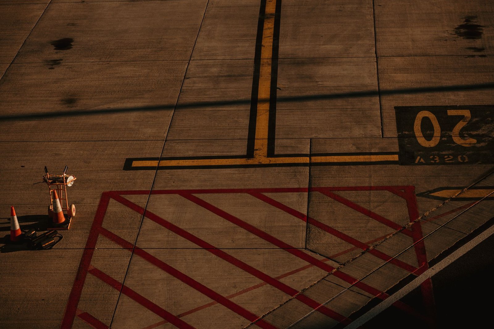 Aerial view of a tarmac with traffic cones and vivid lines during sunset at Luton Airport.