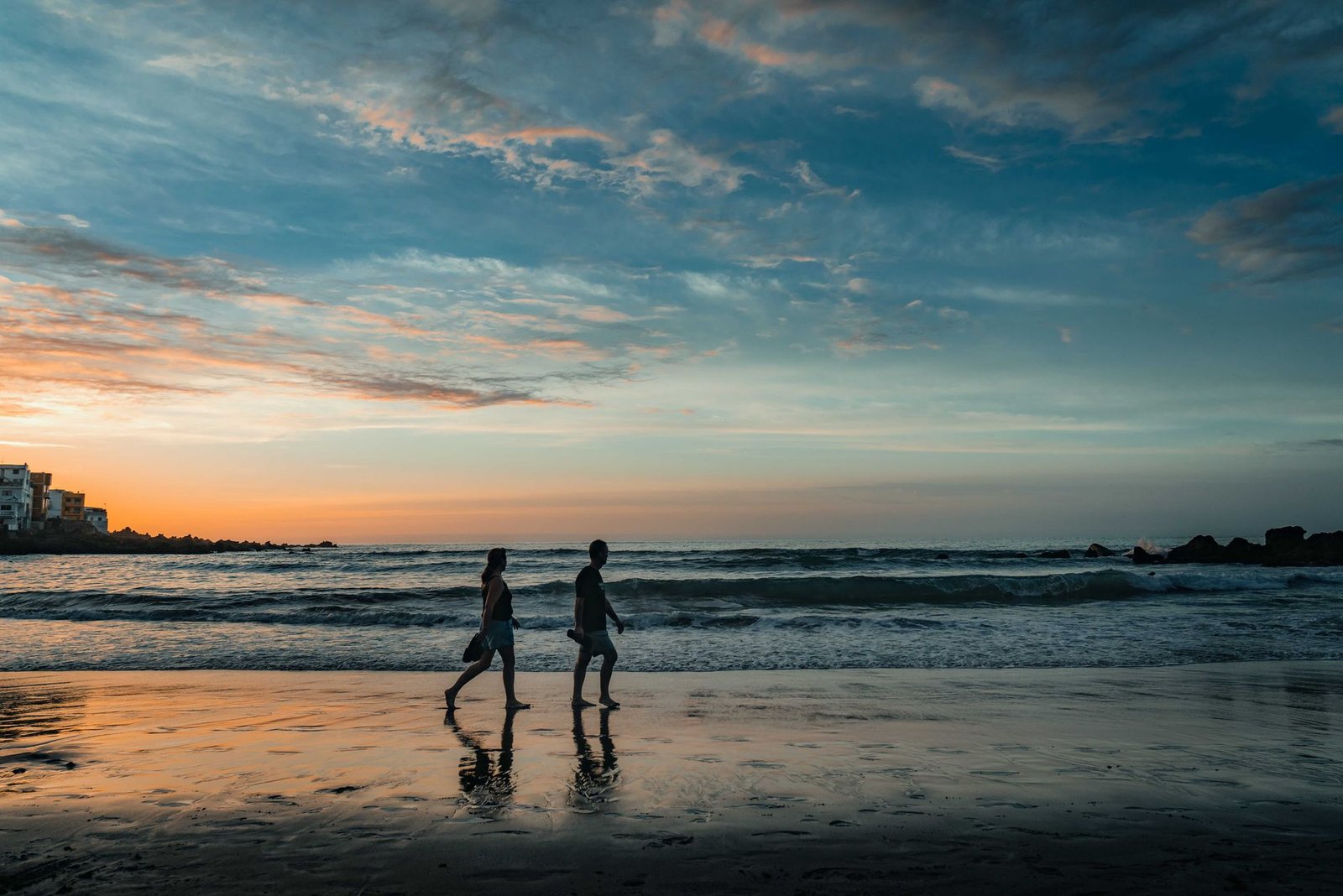 A couple walking along the beach at sunrise in Puerto de la Cruz, Spain, capturing a serene and romantic moment.