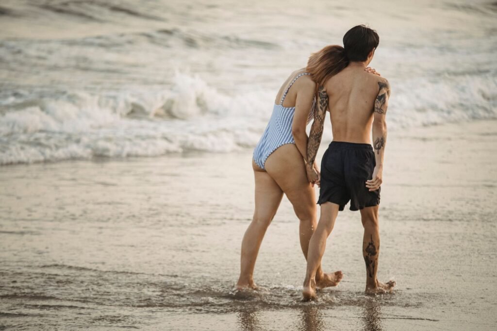 Romantic couple walking on the beach at sunset, embracing love and summer vibes.