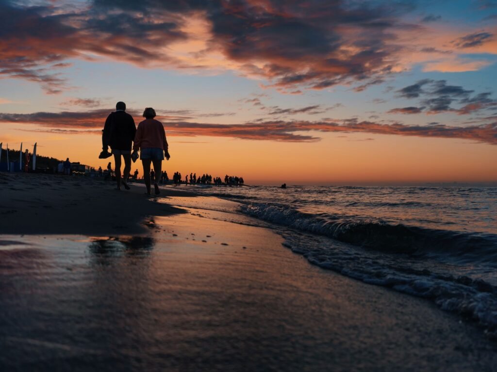 A tranquil silhouette of a couple walking along the beach at sunset, capturing the serene beauty of the sea and sky.