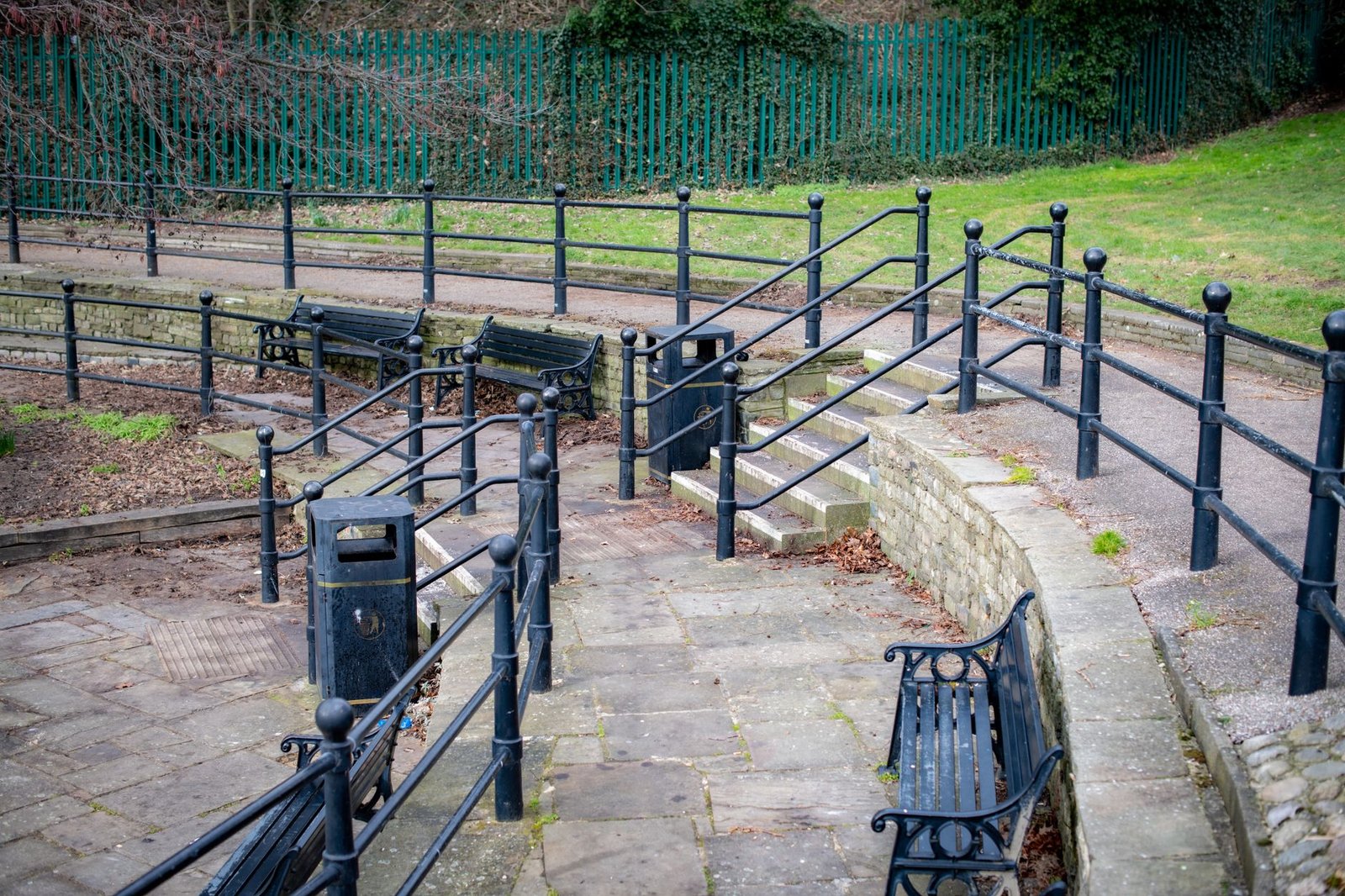 A serene outdoor park scene featuring benches, railings, and paved walkways in Chelmsford, England.