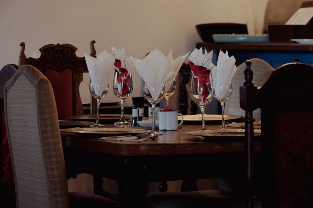 A beautifully set vintage table in a cozy restaurant, featuring elegant glassware and ornate chairs.