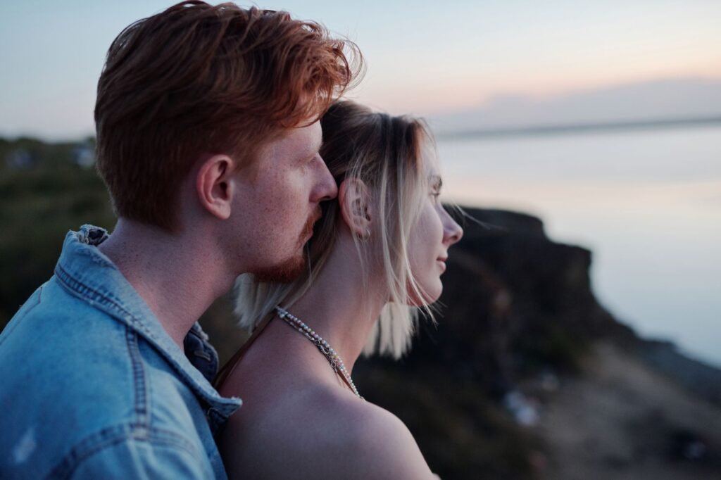 A couple shares a tender moment embracing by the seaside during sunset.