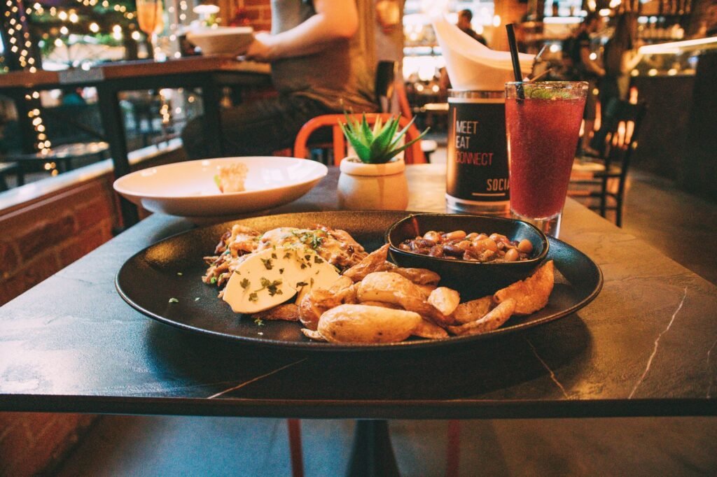 Plate of seasoned potatoes and a refreshing drink on a table in a cozy restaurant setting.
