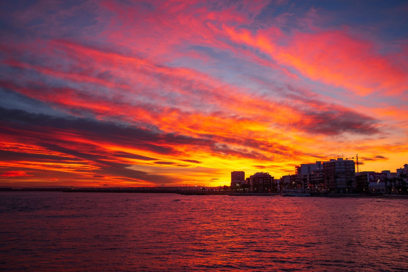 Breathtaking sunset over the sea with vibrant orange and pink clouds in Torrevieja, Spain.