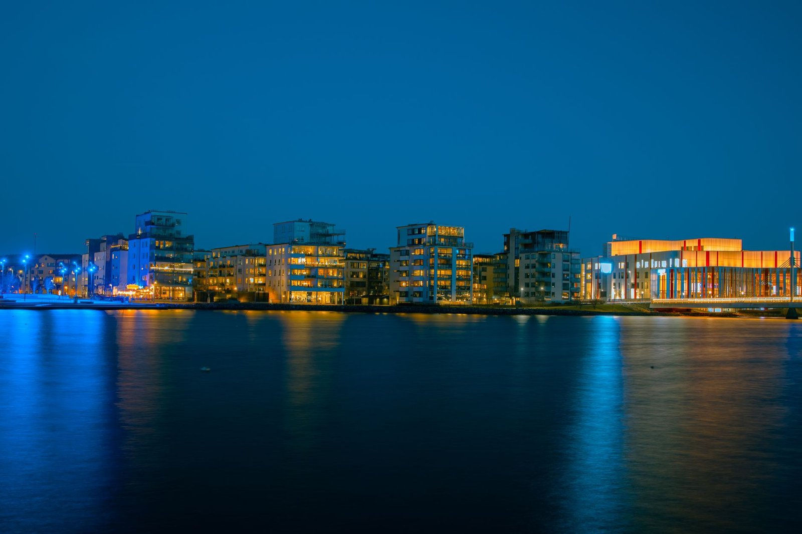 Beautiful night view of Jönköping's illuminated waterfront buildings reflecting on the water.