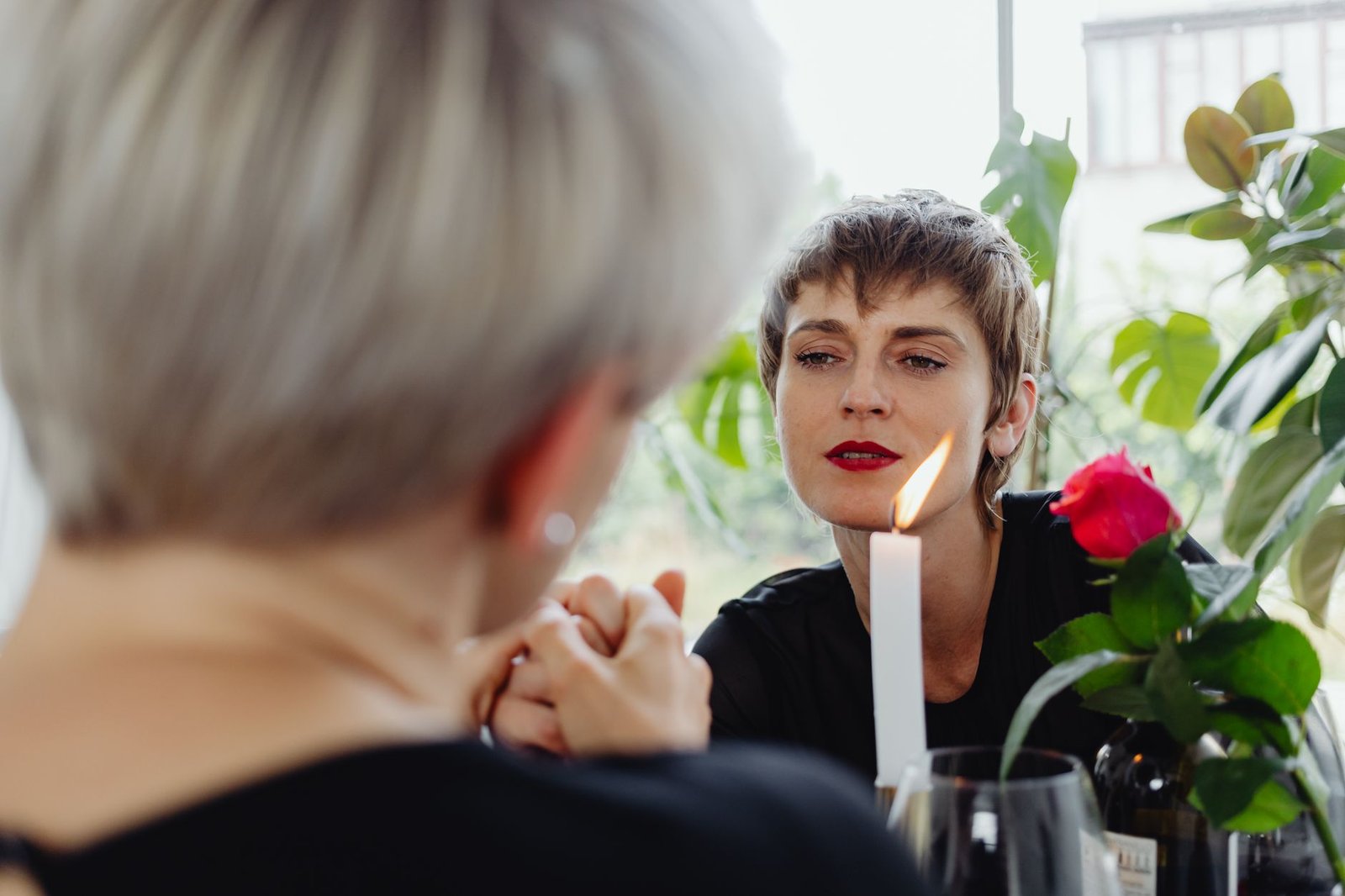 A loving lesbian couple enjoying a romantic candlelit dinner with red roses.