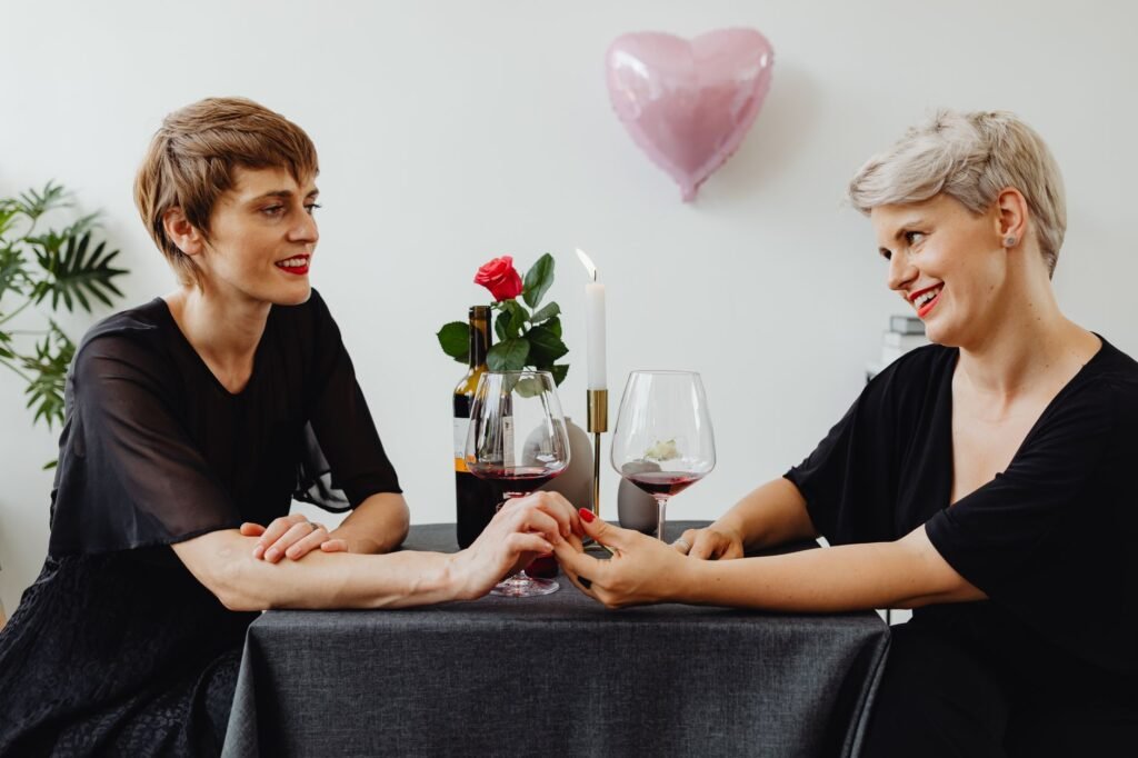 Two women enjoying a romantic dinner with wine and roses, creating a loving atmosphere.