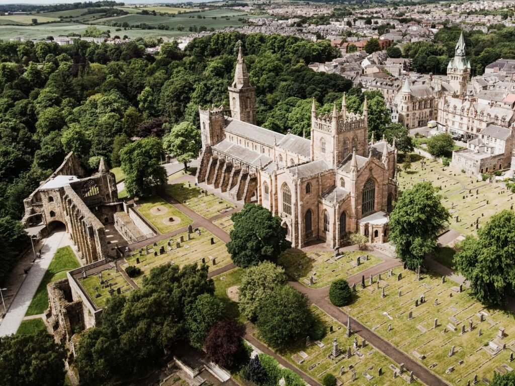 Aerial shot of a historic cathedral surrounded by trees and a cemetery.