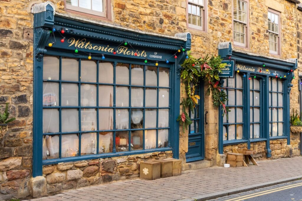 Old-fashioned florist shop with festive lights in Corbridge village, capturing holiday spirit.