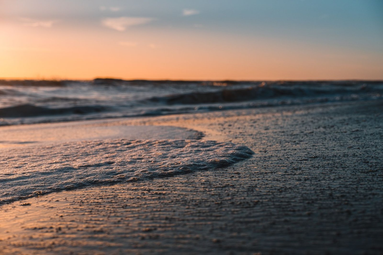 Tranquil Cocoa Beach during sunset with waves gently washing over sandy shore.