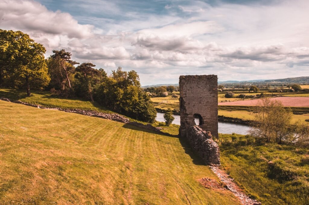 Serene landscape view of historic ruins by a river surrounded by lush greenery; perfect for nature lovers.