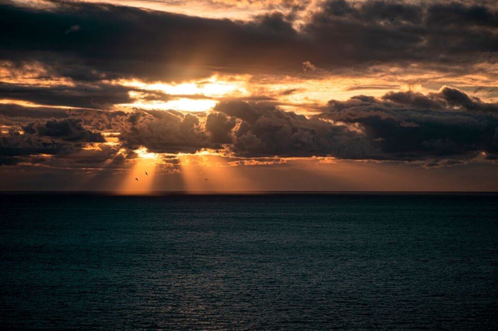 Beautiful sunset over the sea in Toscana, Italy, with dramatic clouds and sunbeams.
