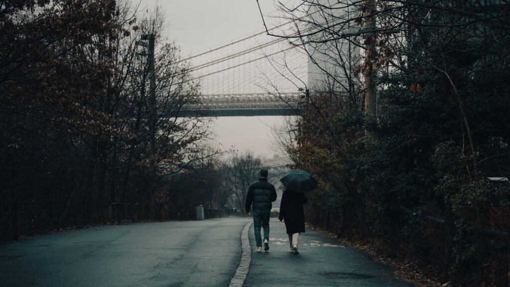 Couple walking with an umbrella near Brooklyn Bridge on a rainy day in NYC.