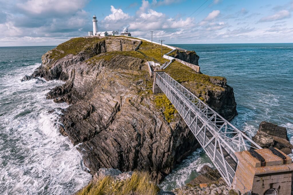 Stunning coastal view of South Stack Lighthouse on Anglesey, Wales, with rocky cliffs and ocean waves.