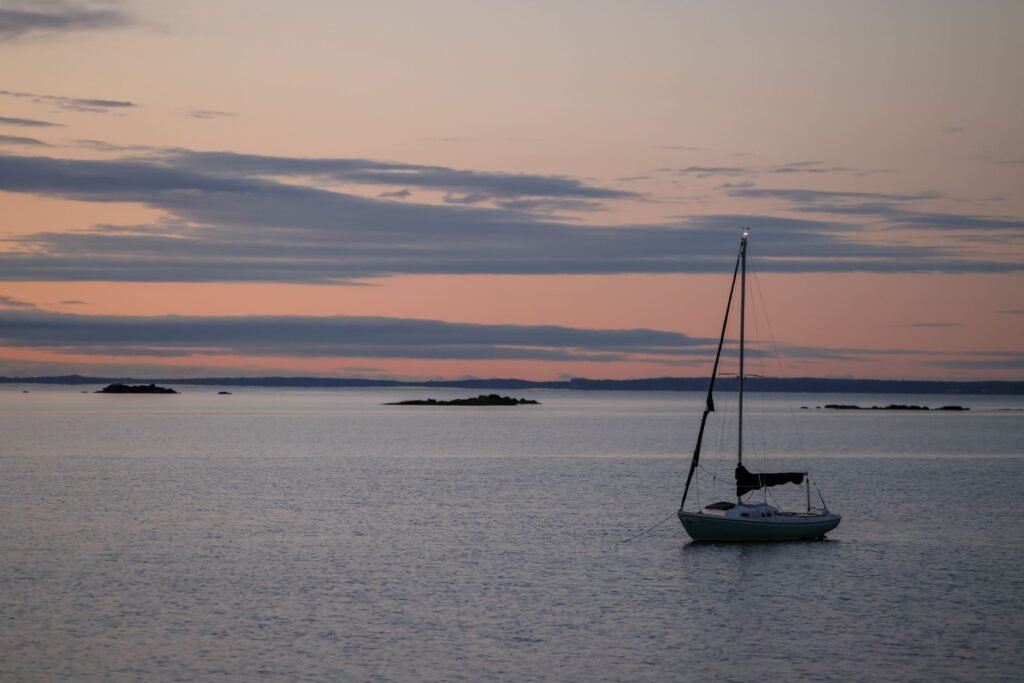 Serene scene of a sailboat at sunset on the Stamford, CT coastline, evoking tranquility.