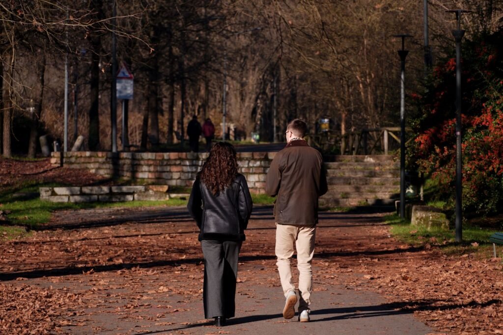 Couple enjoying a peaceful autumn walk in a picturesque Milan park setting.