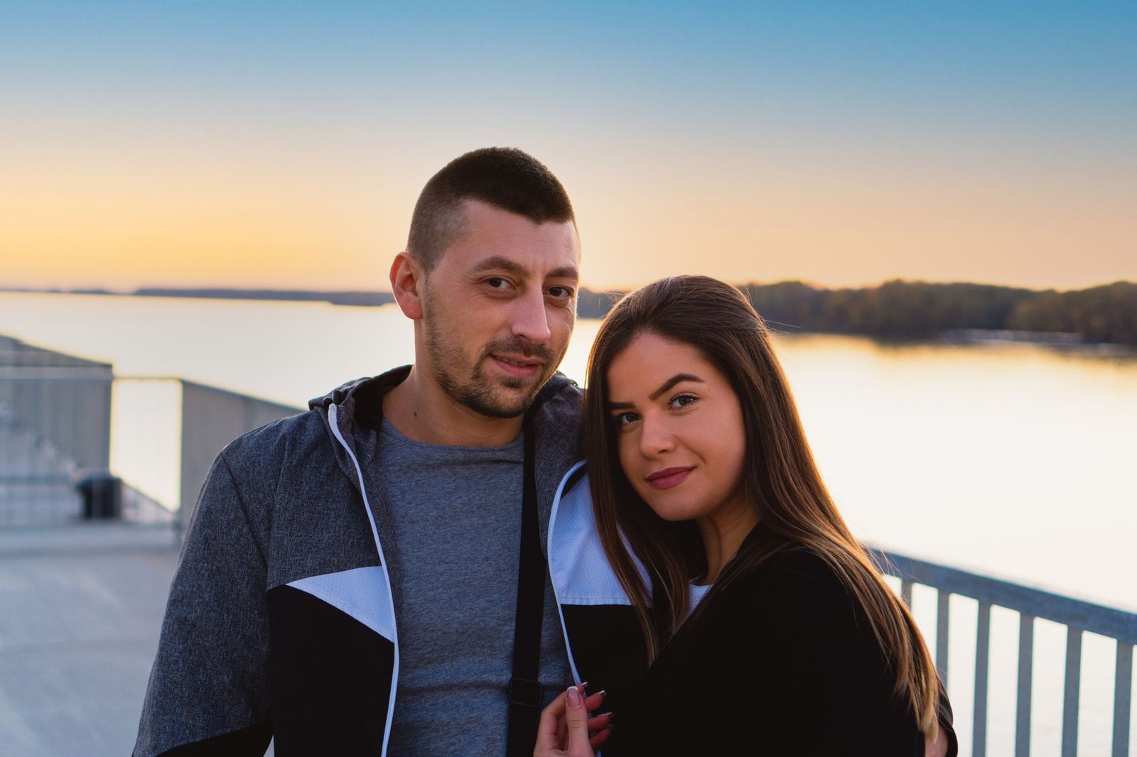 A loving couple embracing by a tranquil lake during sunset, capturing a moment of togetherness.