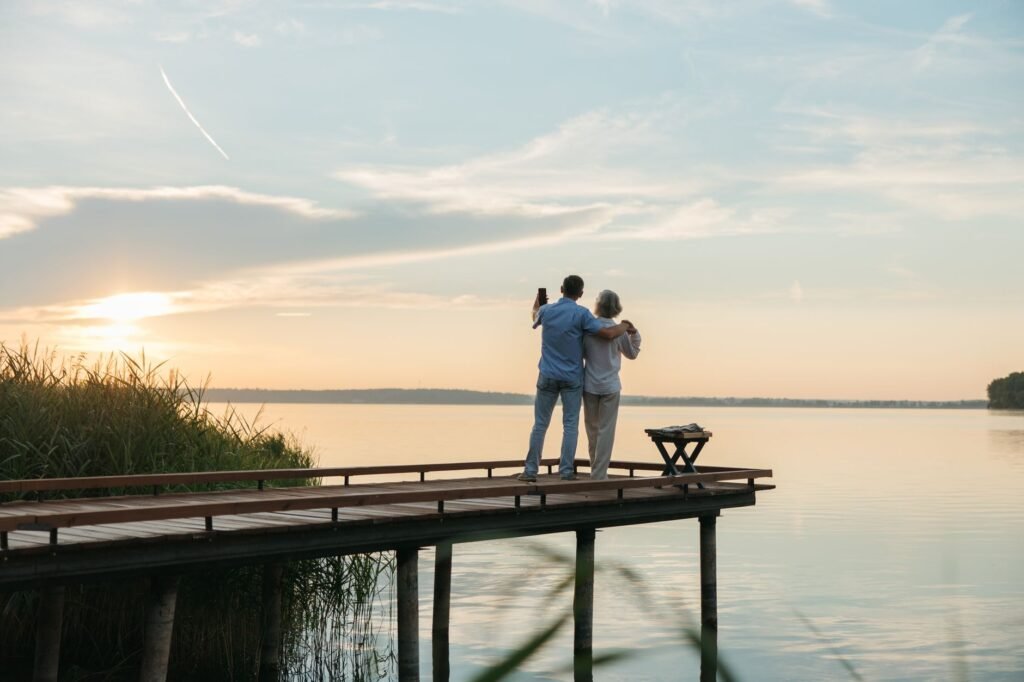 Couple enjoying a serene sunset on a wooden dock by the water.