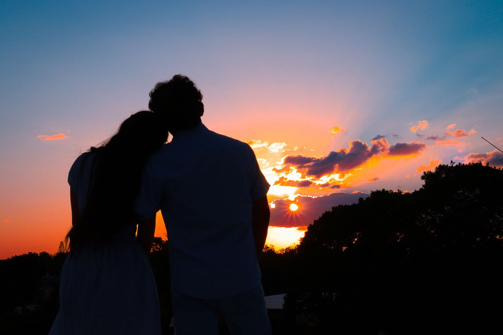 Silhouetted couple embracing at sunset, creating a romantic and serene atmosphere.