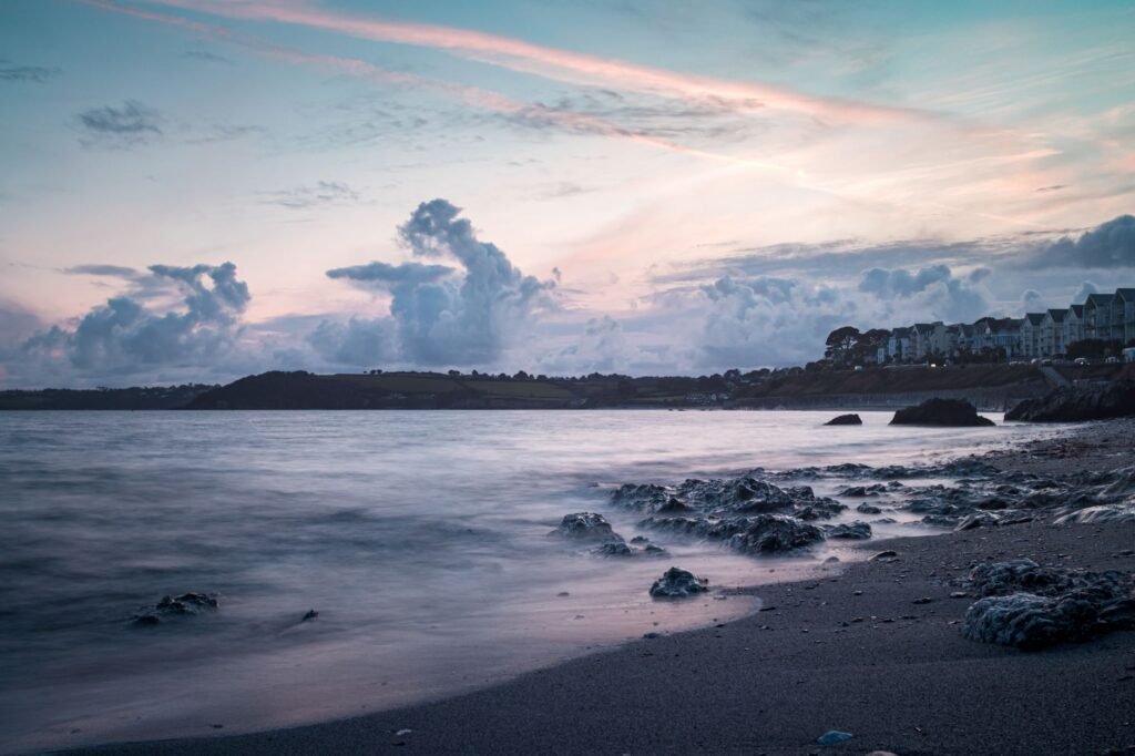 Breathtaking sunset view of Falmouth's rocky beach and tranquil sea, offering a peaceful escape.
