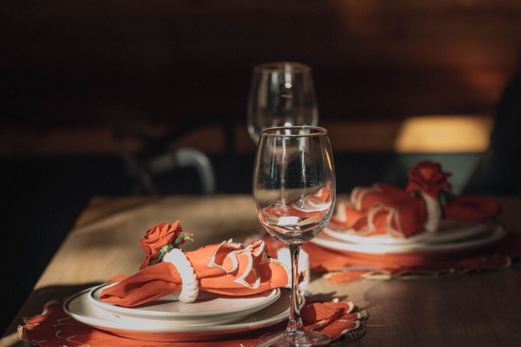 Elegant dining table with wine glasses and red rose napkin decorations, perfect for romantic settings.