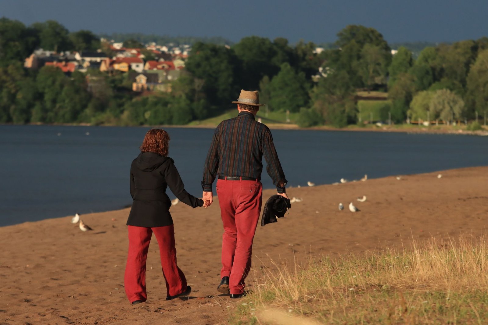 Romantic couple holding hands and walking along Jönköping lakeside in Sweden.