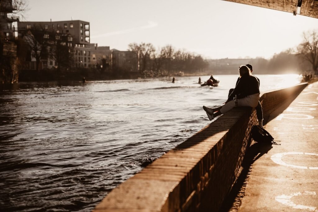 Couple sitting by the river in Ulm, enjoying a romantic sunset. Perfect urban and love-themed stock photo.