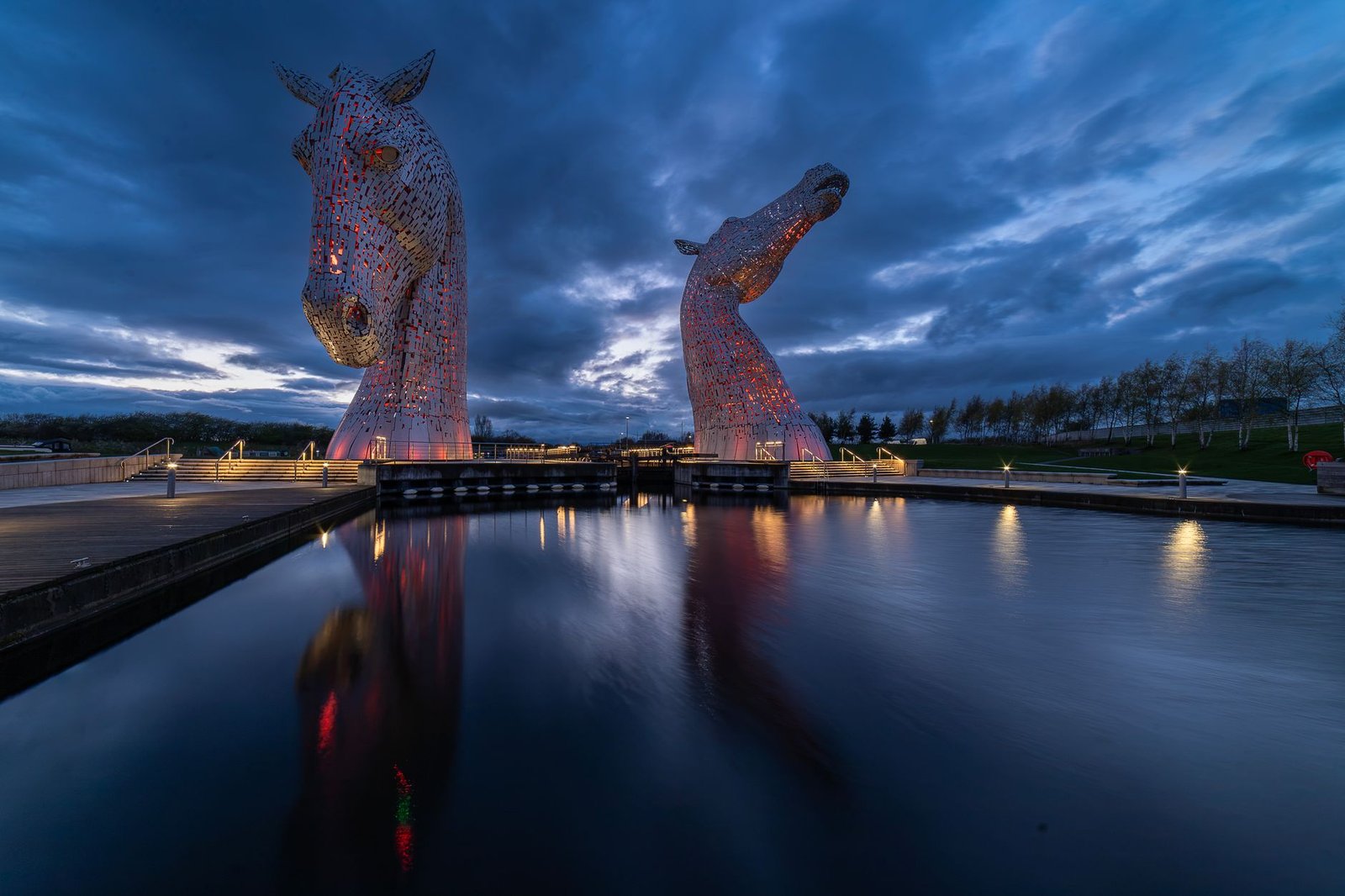 Stunning view of The Kelpies sculptures at dusk reflecting on the calm water.