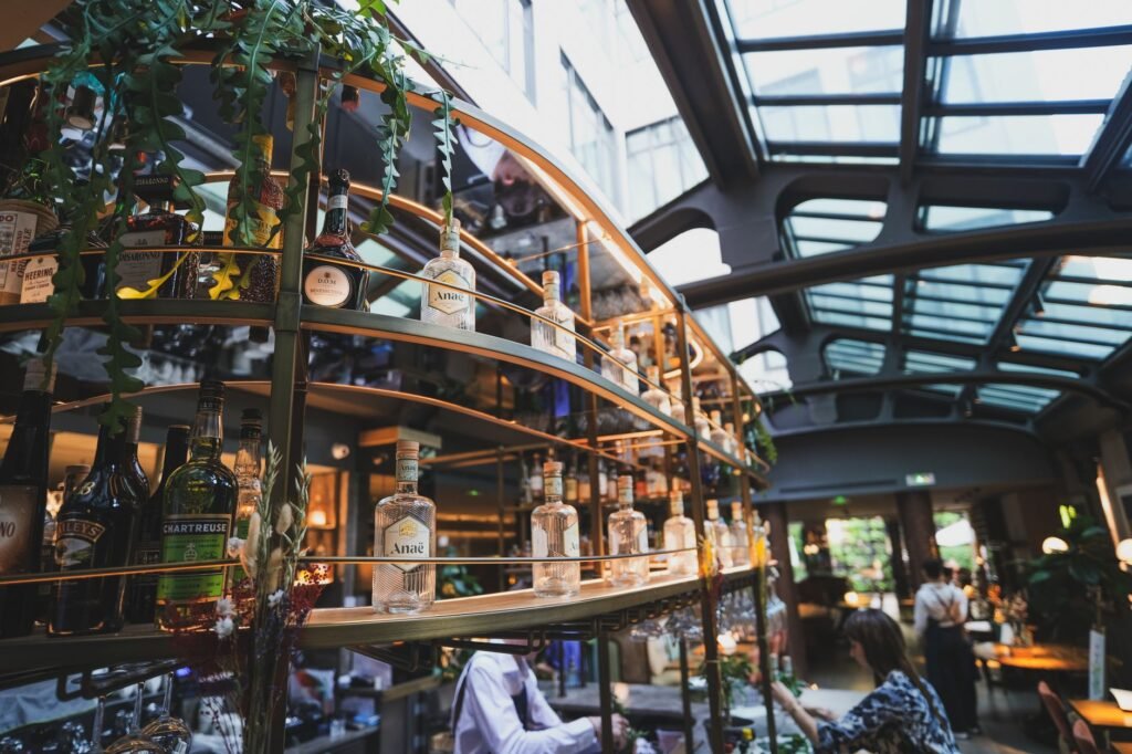 A sophisticated bar interior under a glass ceiling with a variety of alcohol bottles on display.