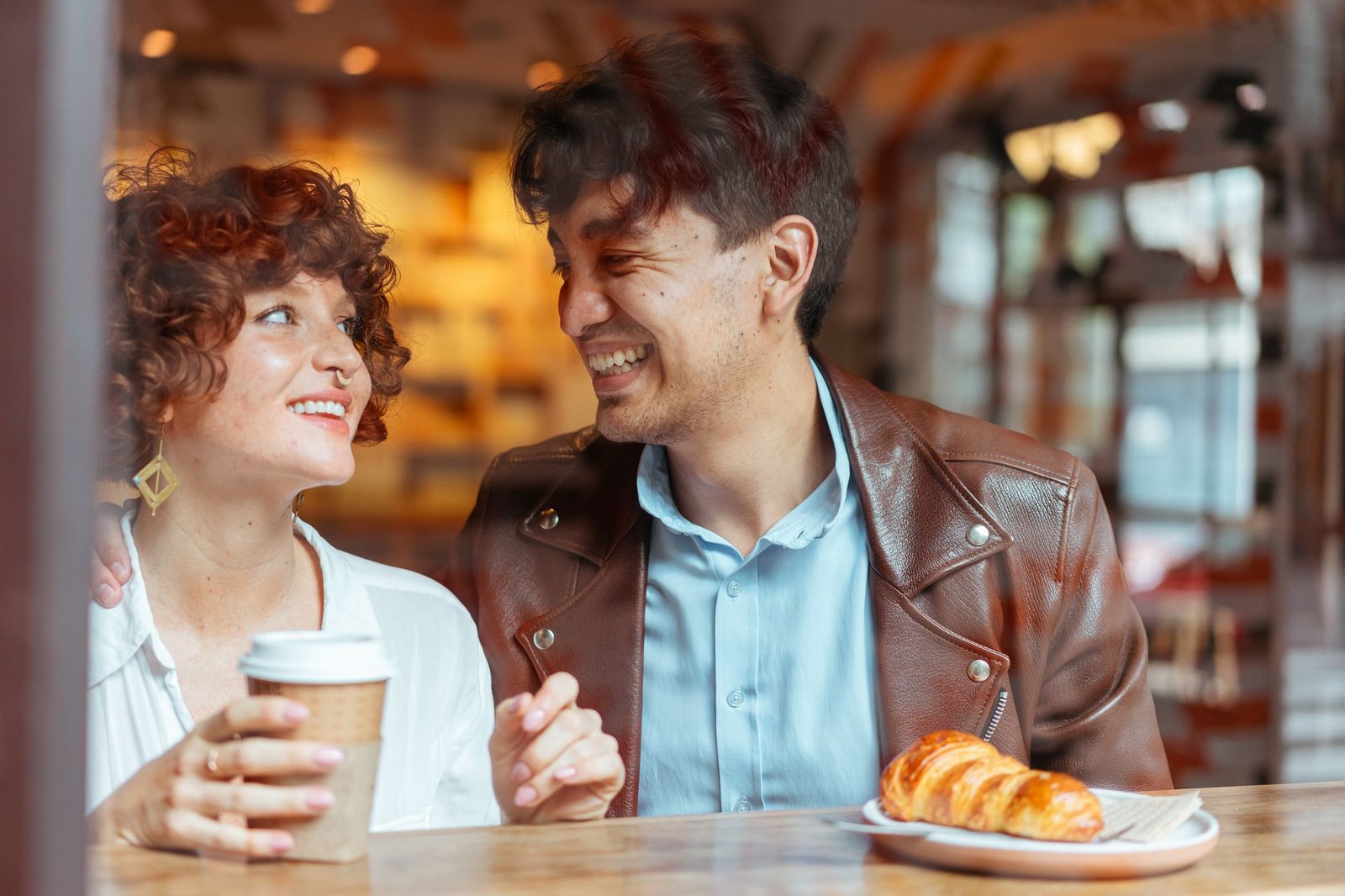 Two adults talking indoors beside a rain-speckled window