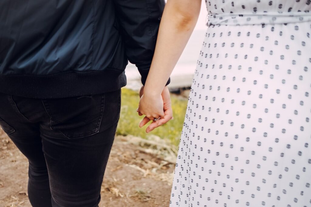 Close-up of a couple holding hands, showcasing love and connection in an outdoor setting.
