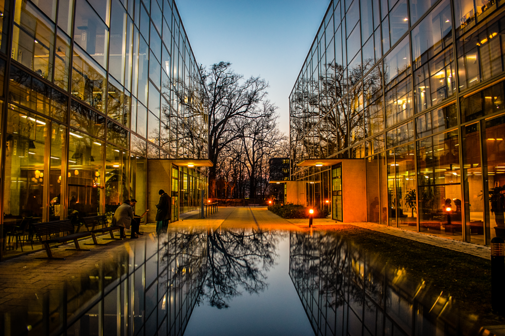 Modern glass buildings with stunning reflections during sunset, creating a serene urban scene.