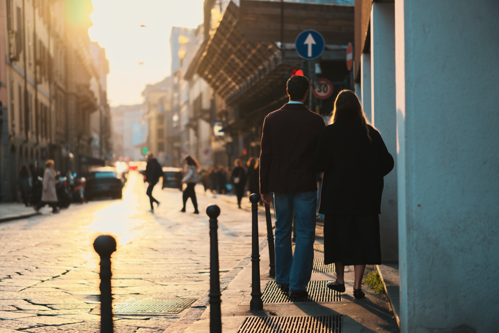Couple walking arm-in-arm down a Milan street during sunset, capturing a warm and romantic atmosphere.