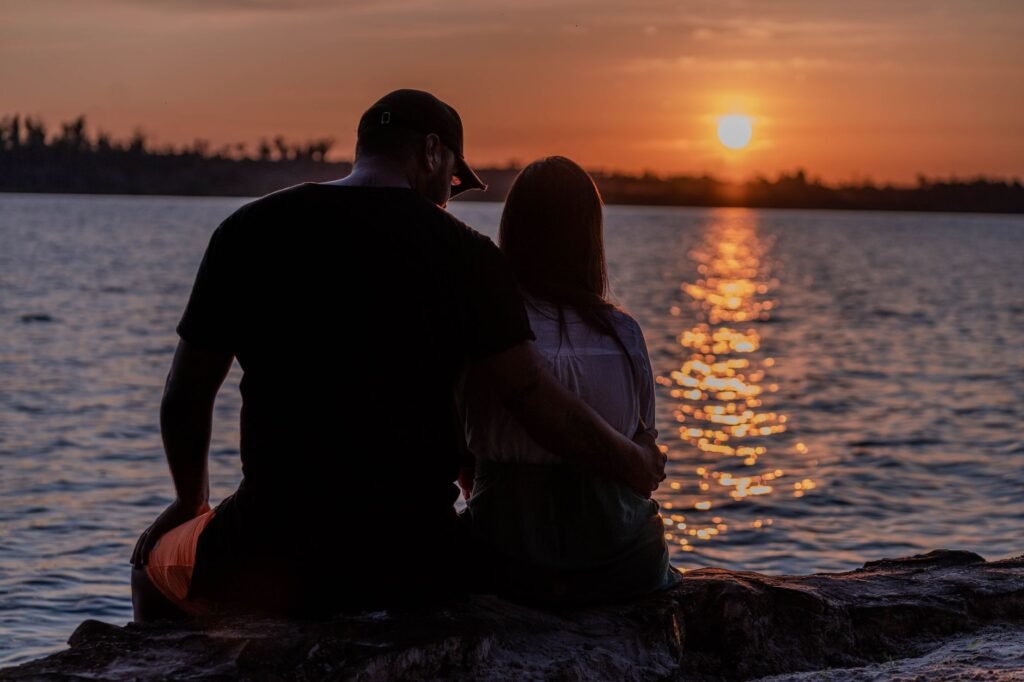 A couple shares a romantic embrace by the seaside during a stunning sunset, reflecting love and tranquility.