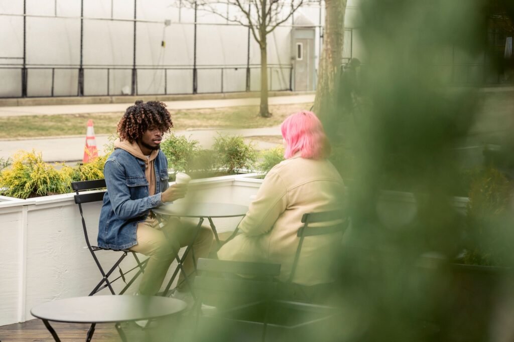 Diverse man and woman sitting at table and talking on autumn day in street cafe