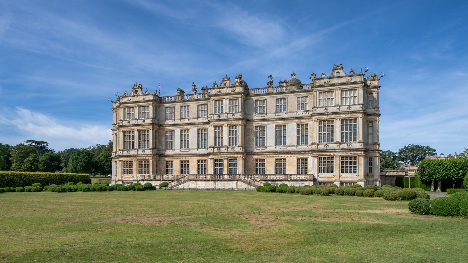 Stunning view of a historic English manor house in a sunny landscape.