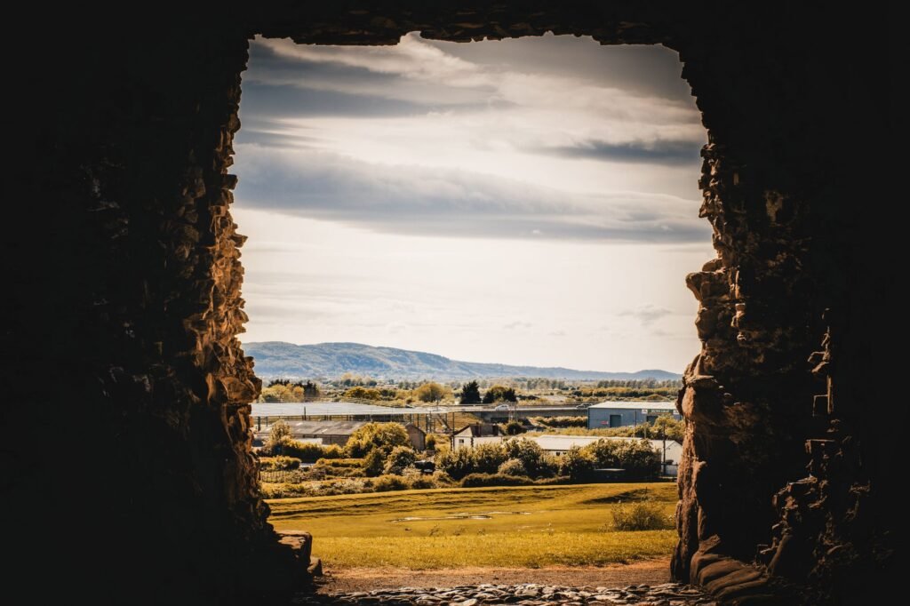 A breathtaking view of the countryside seen through the opening of ancient stone ruins.