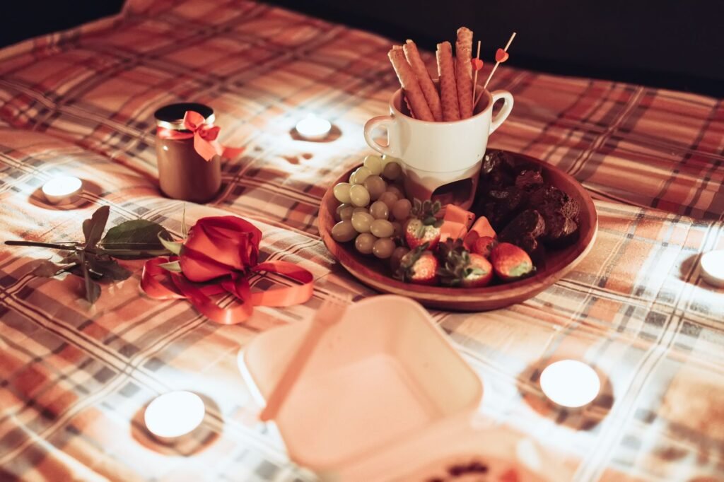 Cozy picnic scene with a plaid blanket, candles, and assorted snacks for a romantic ambiance.