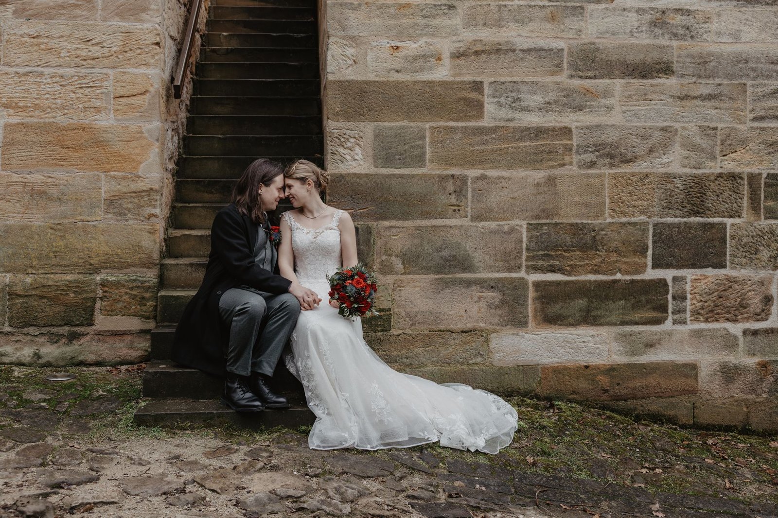 Romantic wedding couple sitting on stairs at an outdoor historical venue, Germany.