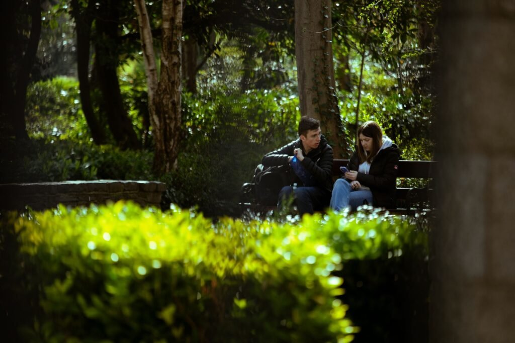 A serene scene featuring a couple seated on a park bench amidst lush greenery in Dublin.